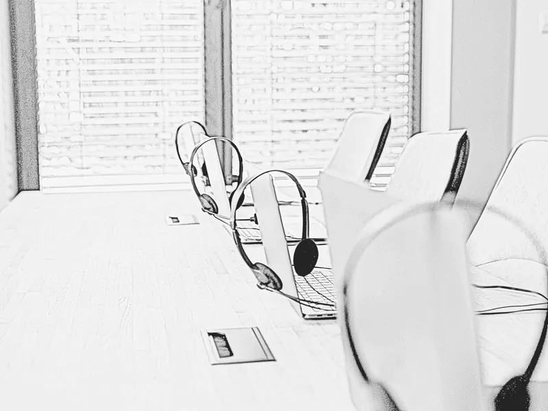 Graphite sketch of laptops and headsets arranged along a shared customer-service desk.