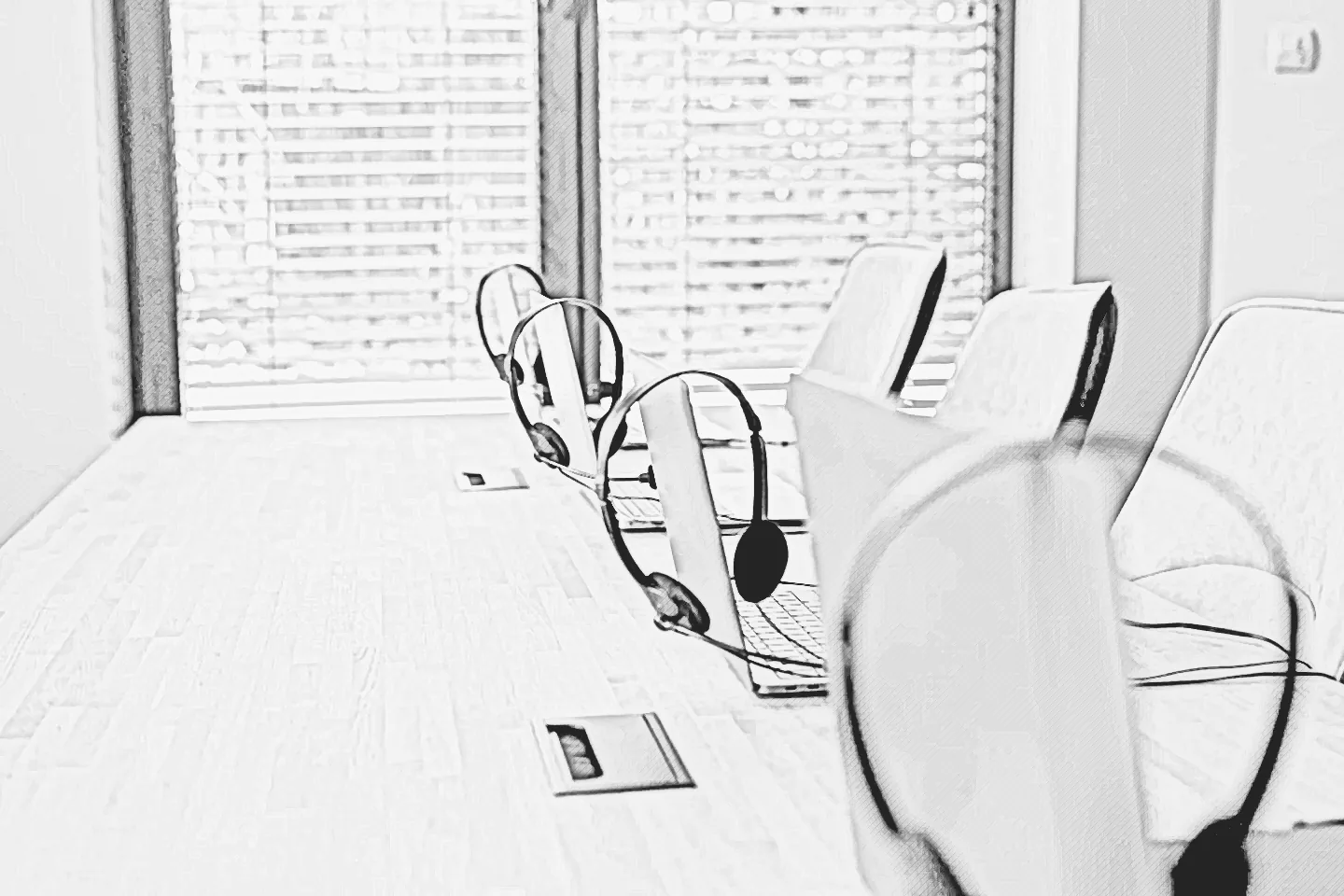 Graphite sketch of laptops and headsets at a shared desk.